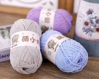 May include: Three skeins of yarn in different colors: light gray, lavender, and light blue. Each skein has a label with a cartoon bear and the text "萌小熊".