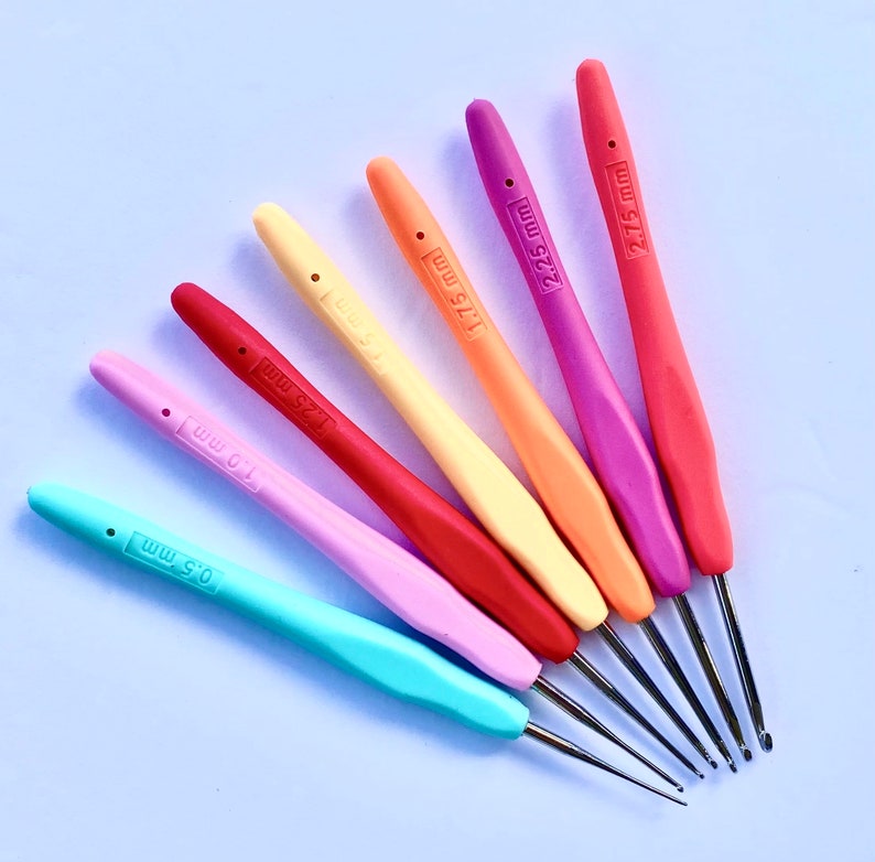 Pu&ograve; includere: Un set di sette uncinetti colorati con punte in metallo. Gli uncinetti sono etichettati con le loro dimensioni in millimetri: 0,5 mm, 1,0 mm, 1,25 mm, 1,75 mm, 2,25 mm, 2,75 mm e 5 mm.