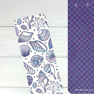 May include: Two bookmarks, one with a purple and blue plaid pattern and the other with a white background and a repeating pattern of seashells and starfish in shades of blue and purple. The bookmark with the plaid pattern has the text "Purple Possessions" at the bottom.