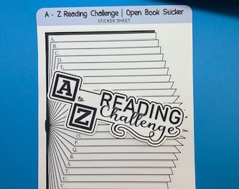 May include: A sticker sheet with a black and white open book design. The book has the letters A to Z on the spine and the words "Reading Challenge" on a banner. The sticker sheet is for an A to Z reading challenge.