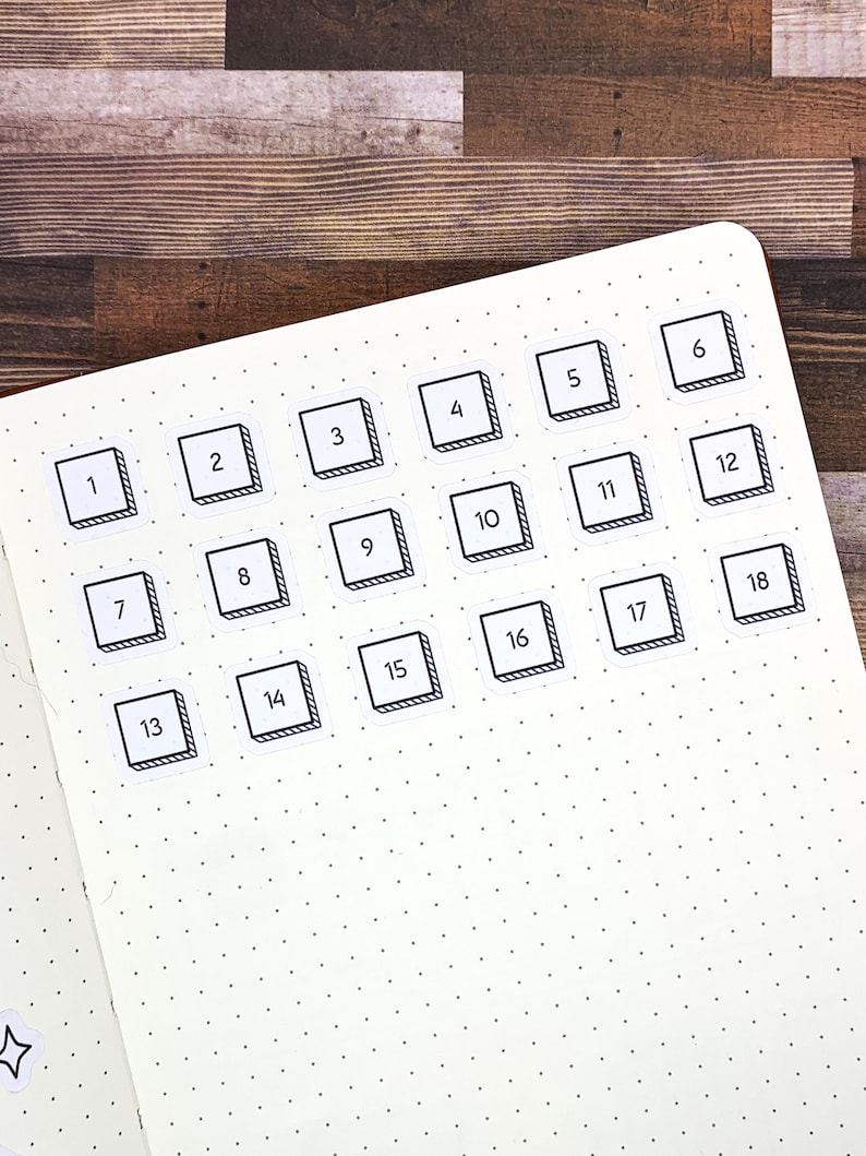 May include: White planner page with black and white numbered stickers from 1 to 18. The stickers are in a grid pattern and have a black outline with a white interior. The numbers are black and centered within the stickers.