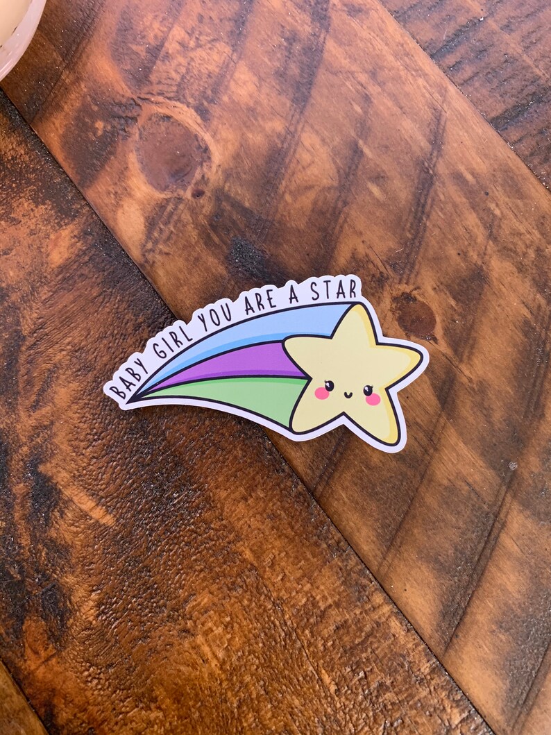 May include: A yellow star with a smiling face, with a rainbow tail and the text "BABY GIRL YOU ARE A STAR" in black.