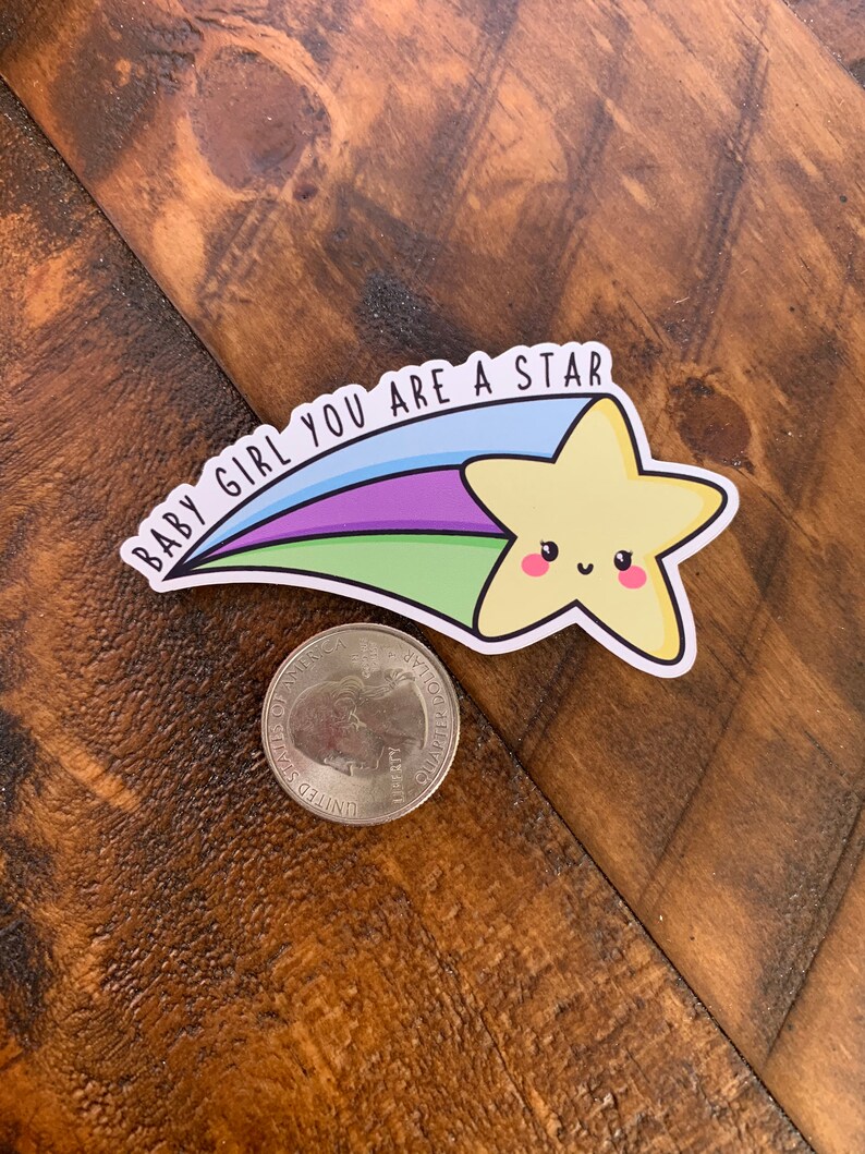 May include: A yellow star with a smiling face, with a rainbow tail and the text "Baby Girl You Are A Star" on a wooden background.