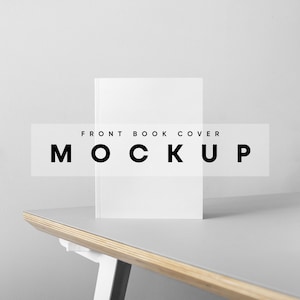 Puede incluir: Una maqueta de portada de libro blanca sobre una mesa gris con un borde de madera. El texto "FRONT BOOK COVER MOCKUP" es visible en la imagen.