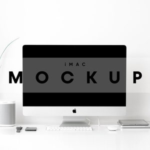 May include: A white iMac computer with a black screen displaying the text "iMac MOCKUP". The computer is on a white desk with a white keyboard, a white mouse, a silver speaker, a black watch, and a silver tablet.