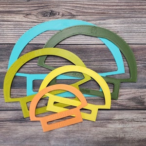 May include: Four plastic semi-circle shapes in different sizes, stacked on top of each other. The shapes are turquoise, green, yellow, and orange.