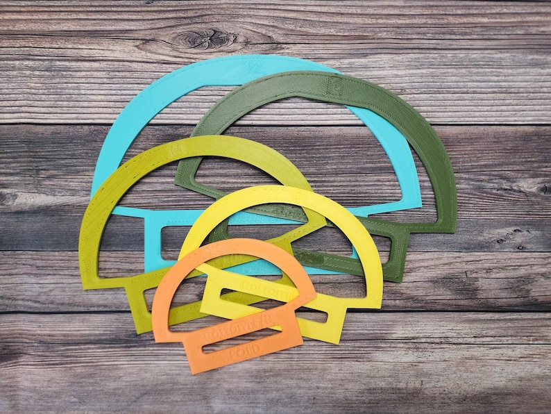 May include: Four plastic semi-circle shapes in different sizes, stacked on top of each other. The shapes are turquoise, green, yellow, and orange.
