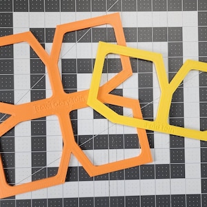 May include: Two plastic stencils, one orange and one yellow, with geometric shapes. The orange stencil has the text "Rowicozy" on it, and the yellow stencil has the text "Fold 101b" on it.