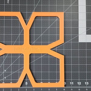 May include: Orange plastic template with a geometric design and the text "Bowlcony Toih" printed on it.
