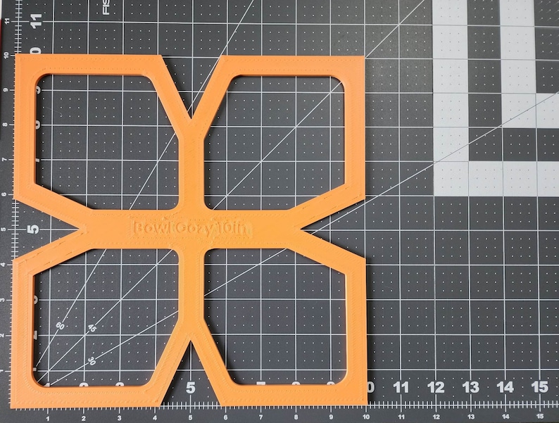 May include: Orange plastic template with a geometric design and the text "Bowlcony Toih" printed on it.
