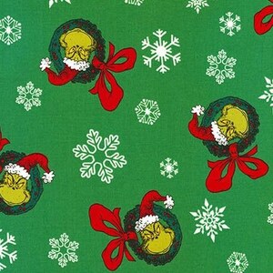 May include: Green wrapping paper with a repeating pattern of white snowflakes and a Grinch character wearing a Santa hat and holding a wreath. The Grinch is green with a grumpy expression.