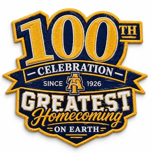 May include: A navy blue and gold embroidered patch featuring the text 100TH CELEBRATION SINCE 1926 AT GREATEST HOMECOMING ON EARTH. The design includes a central monogram logo and bold lettering with a thick gold border and detailed stitching.