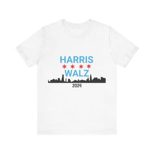 Peut inclure: T-shirt blanc avec une silhouette noire de l'horizon de Chicago et le texte "HARRIS WALZ 2024" en bleu et rouge.