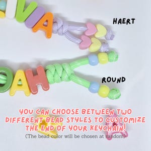 May include: Two personalized keychains featuring colorful plastic letter beads spelling names. One keychain has heart-shaped beads at the ends labeled HAERT, and the other has round beads labeled ROUND. Text states: YOU CAN CHOOSE BETWEEN TWO DIFFERENT BEAD STYLES TO CUSTOMIZE THE END OF YOUR KEYCHAIN! (The bead color will be chosen at random).
