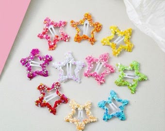 May include: A collection of ten star-shaped hair clips in various colors including pink, orange, yellow, purple, white, red, green, and blue. Each clip features a hollow star frame filled with small star-shaped glitter and a white metal snap clip.