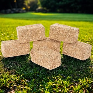 May include: A collection of five rectangular blocks made of compressed light brown wood shavings. The blocks are arranged in a cluster, each featuring a rough, fibrous texture consistent with wood fiber material, showing a natural tan color.