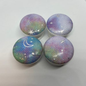May include: Four round, white ceramic knobs with a rainbow watercolour design and silver glitter stars and a crescent moon.