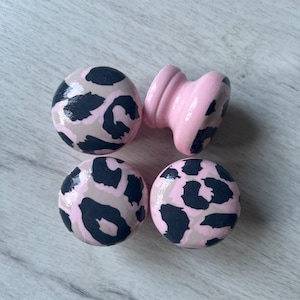 May include: Four wooden knobs with a pink base and black and beige leopard print design.