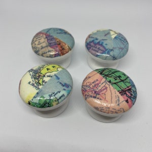 May include: Four white ceramic knobs with a vintage world map design. Each knob features a different section of the map, including Africa, Asia, Europe, and North America.