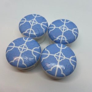 May include: Four blue ceramic knobs with a white geometric pattern. The knobs are round and have a glossy finish.