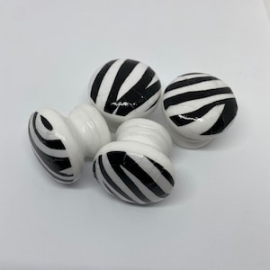 May include: Four white ceramic drawer knobs with black and white zebra print designs.