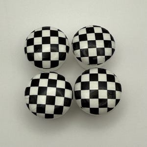 May include: Four spherical objects with a black and white chequered pattern. They are arranged in a square formation against a white background. The chequered pattern is consistent across all four objects.