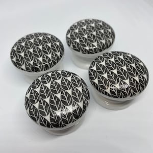 May include: Four white ceramic knobs with a black and white leaf pattern.