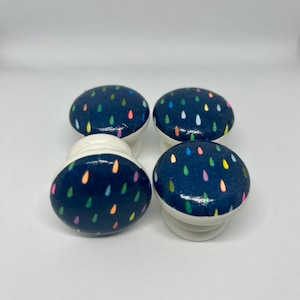 May include: Four blue and white ceramic knobs with a colourful raindrop pattern.