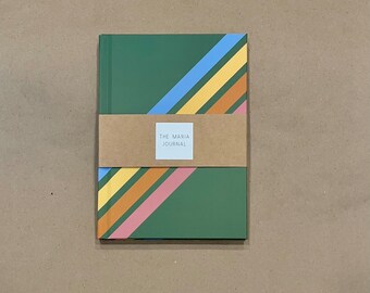 May include: A green journal with diagonal stripes in blue, yellow, orange, and pink. The journal is wrapped with a brown paper band that has a white label with the text "THE MARIA JOURNAL".