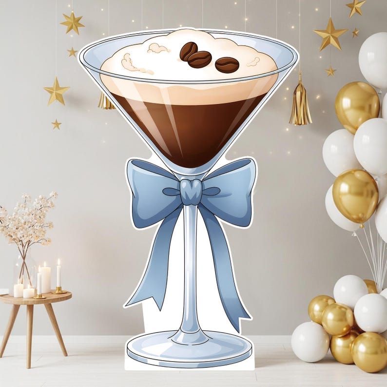 May include: A large, flat, die-cut cardboard cutout of a martini glass filled with dark brown coffee liquid, topped with white foam and three dark brown coffee beans. A light blue decorative bow is tied around the stem of the glass.