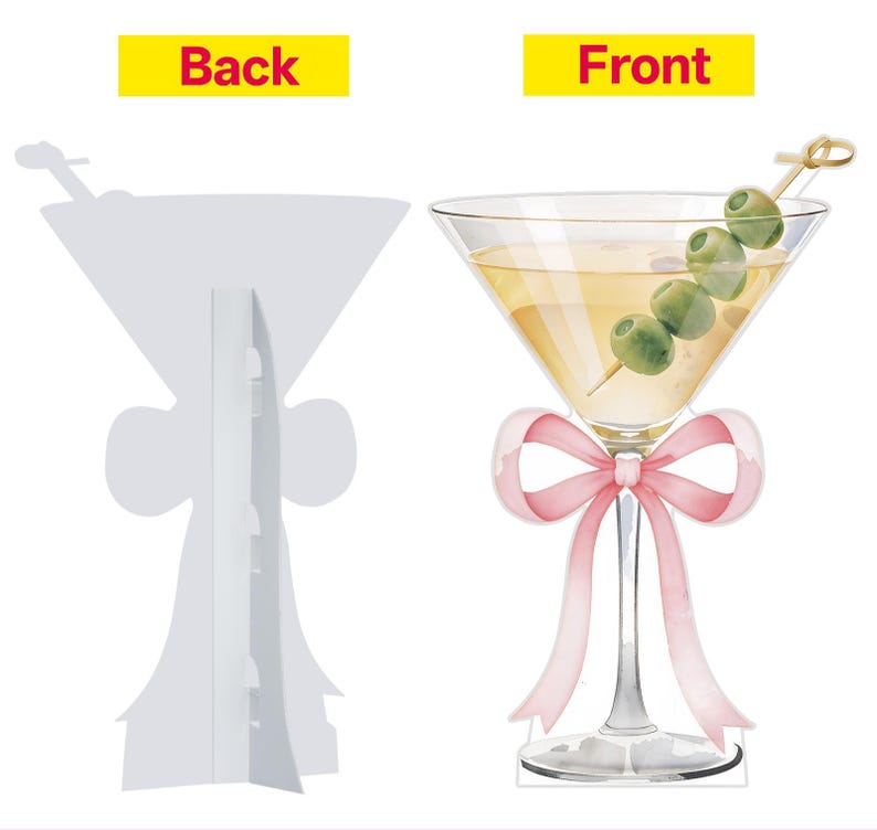 May include: A double-sided cardboard cutout featuring a martini glass illustration. The front displays a yellow cocktail with four green olives on a pick and a pink ribbon tied around the stem. The back is plain white with a fold-out support stand.