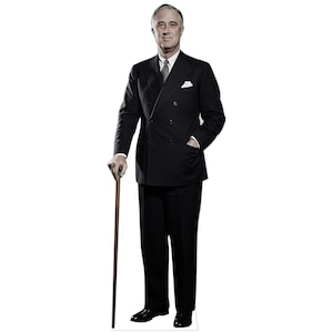 May include: A life-size cardboard cutout of Franklin D. Roosevelt wearing a dark double-breasted suit, a white shirt, a patterned tie, and a white pocket square. He is standing upright, holding a thin wooden walking cane in his right hand.