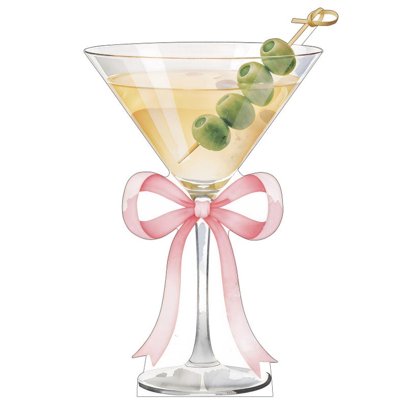 May include: A martini glass filled with a pale yellow liquid and garnished with three green olives on a wooden cocktail pick. A light pink ribbon is tied in a bow around the stem of the glass, which features a wide bowl and a clear base.