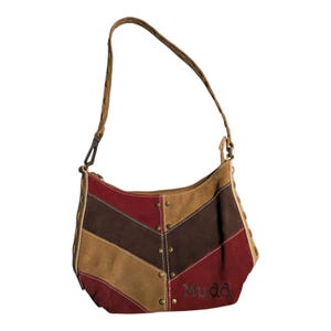 May include: A shoulder bag with a chevron pattern in shades of brown, tan, and burgundy. The bag has a brown strap and the word "Mudd" is embroidered on the front. Metal studs accent the seams.