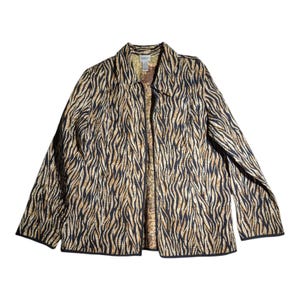 Puede incluir: Una chaqueta de manga larga con un estampado animal negro y dorado similar al de una cebra. La prenda tiene cuello, cierre frontal de botones y un forro interior visible con un patrón abstracto multicolor. La chaqueta presenta una textura acolchada.