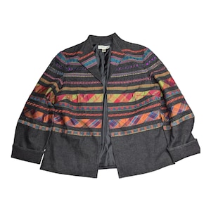 May include: A dark gray blazer with colorful embroidered details. The jacket features horizontal bands of plaid and patterned fabric in shades of orange, red, yellow, and blue. The sleeves are cuffed.