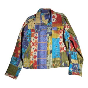 Peut inclure: Une veste à manches longues boutonnée présentant un motif patchwork multicolore avec divers motifs géométriques et floraux dans des tons de rouge, bleu, jaune et vert. Le vêtement comprend un col, deux poches poitrine et des poignets boutonnés.