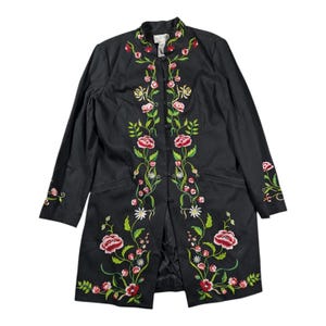 May include: A black long-sleeve jacket featuring a mandarin collar and a front button closure. The garment is decorated with vibrant floral embroidery in shades of red, pink, white, and yellow, with green stems and leaves.