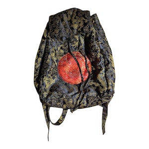 Puede incluir: Mochila negra con cordón, con un patrón de dragón dorado y un emblema circular rojo. La mochila tiene un cierre de cordón y correas para los hombros. La tela tiene un aspecto brillante y texturizado.
