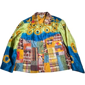 May include: A long-sleeve jacket featuring a vibrant patchwork design with various rectangular fabric segments in shades of orange, yellow, blue, and red. The upper portion displays a bright lime green and blue background with embroidered yellow circular motifs.