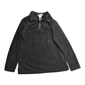 May include: A dark gray fleece pullover with a collared neckline and a quarter-zip closure. The long-sleeved top is embellished with small, scattered rhinestones. The collar has a scalloped edge.