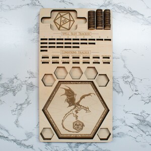May include: Wooden game board with a dragon design, a 20-sided die, and a spell slot tracker. The board also includes a conditions tracker with labels for blinded, charmed, deafened, frightened, grappled, incapacitated,  inured, invisible, paralyzed, petrified, poisoned, prone, restrained, and stunned.