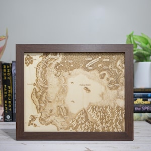 May include: A framed wooden map with a detailed, engraved design. The map features landmasses, water bodies, and text labels, all in a light brown color. The frame is a dark brown, and the map is displayed on a light-colored background.