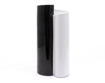 Könnte beinhalten: Eine schwarze und weiße Keramikvase mit einem einzigartigen, modernen Design. Die Vase ist in der Mitte geteilt, eine Seite ist schwarz, die andere weiß.