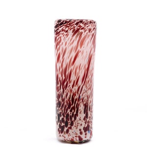 May include: A clear glass shot glass with a pink and brown speckled pattern.