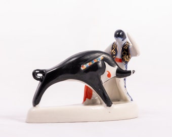 May include: A porcelain figurine of a bullfighter facing a black bull. The bullfighter is wearing a traditional costume with gold accents. The bull is decorated with colorful details.
