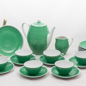 Op de afbeelding: Een complete groen-witte theeset, inclusief een theepot, melkkan, kopjes, schotels en borden. De set heeft een glanzende afwerking en een klassiek design. De borden hebben een diameter van ongeveer 25 cm.