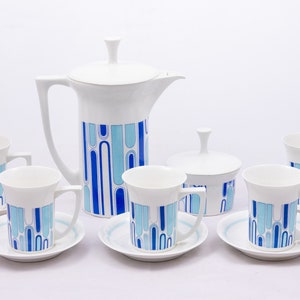 Puede incluir: Un juego de té de porcelana blanca con un patrón geométrico azul y azul claro. El juego incluye una tetera, un azucarero y seis tazas y platillos.