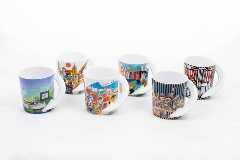 May include: Set of five white ceramic mugs with colourful cityscapes printed on them. Each mug has a unique design and features a whimsical, curved handle.