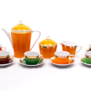 Puede incluir: Un juego de té vintage con una tetera amarilla, una jarra de crema y un azucarero. El juego incluye seis tazas y platillos en varios colores, incluyendo rojo, marrón, verde y naranja.